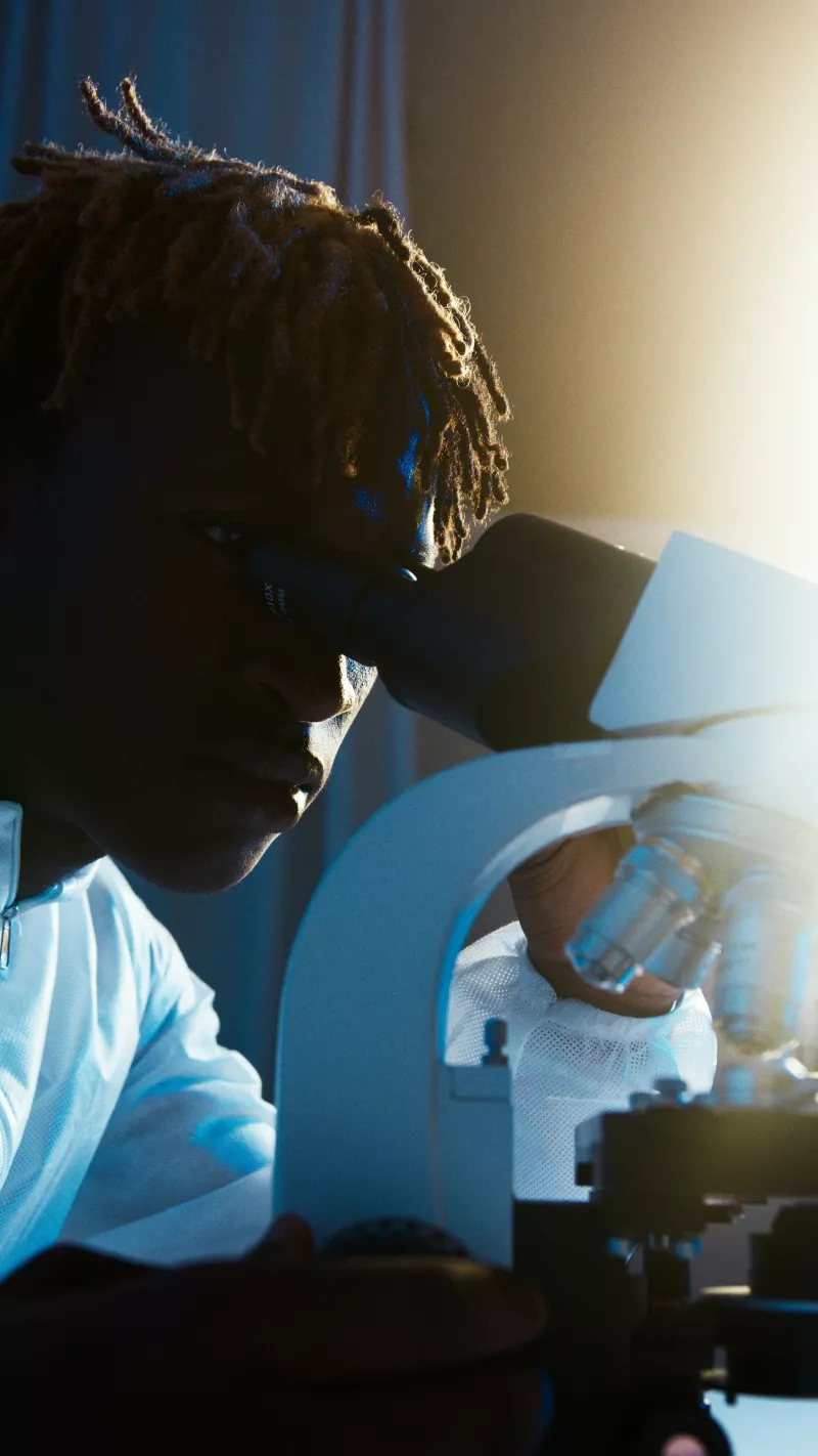 A black male looks through a microscope