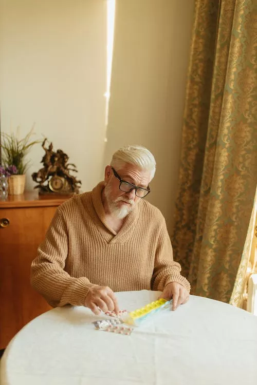 Man in Brown Knitted Sweater Organizing the Medicines