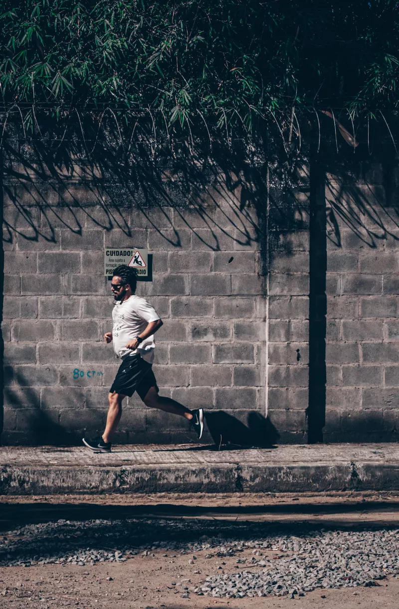 Concentrated ethnic man jogging on roadside