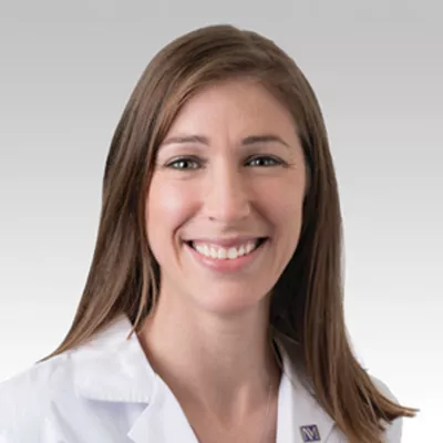 Woman with long brown hair in a white coat, Dr. Alicia Morgans