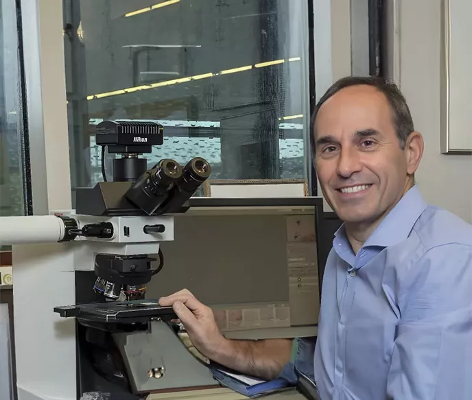 Dr Jonathon Epstein posing next to a Nikon slide viewing microscope