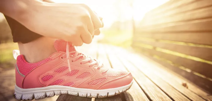 Person ties their shoe on a bench at sunrise ready to run