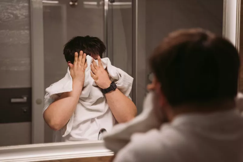 Man in the bathroom tries to wipe his face off with towel