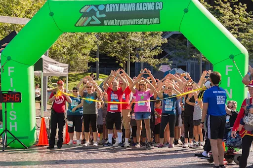 A group of runners under a beginning line in the MidAtlantic Run/Walk