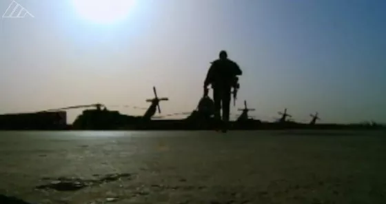 A military personnel walking towards several helicopters