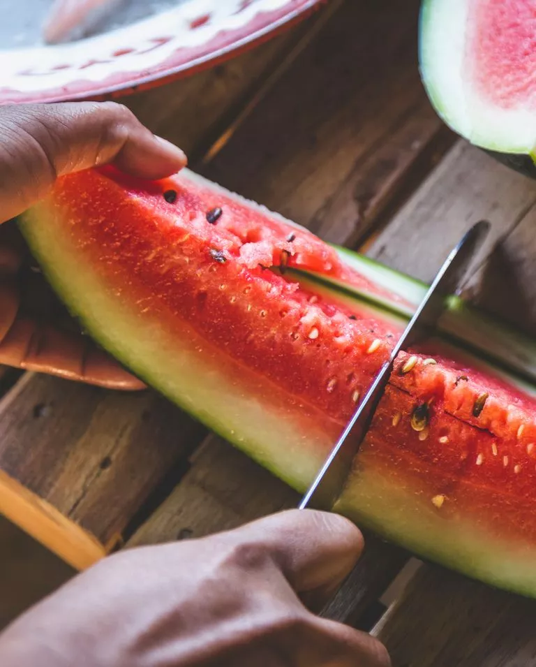 A person slicing a piece of watermellon