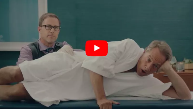 Doctor conducting a digital rectal exam on a male patient in a white gown