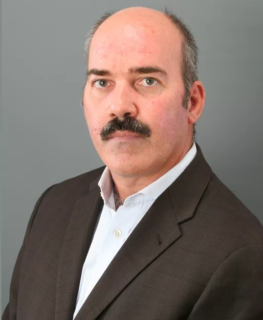 A bold man in a dark suit with moustache