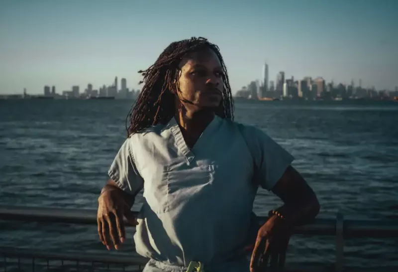 African American doctor with braids standing at a dock with water in the background