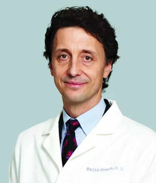 Caucasian man with dark hair wearing a white lab coat