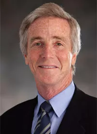 Middle-aged man with greying hair wearing a dark suit