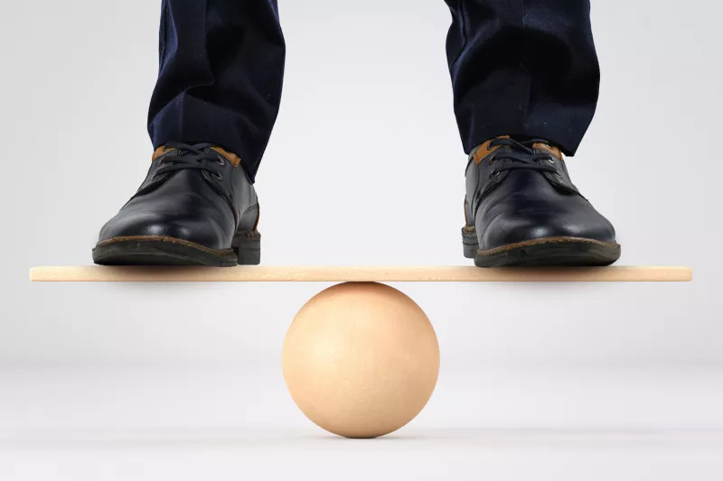 Man dressed up in a suit standing and balancing over a ball