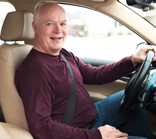 A balding Caucasian man driving a car