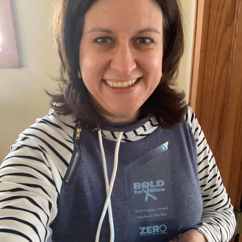 Woman with dark hair holding a Bold for Blue plaque