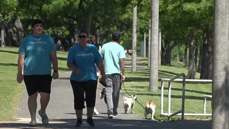 People wearing Neighborly t-shirts walking in a park