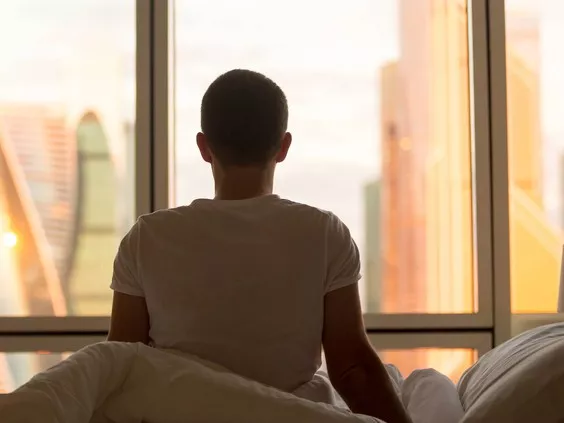 Silhouette of a male with a shaved head looking through a window