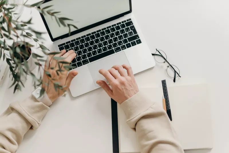 Person in beige long-sleeve shirt using a macbook pro