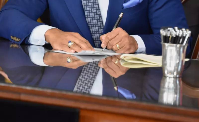 Hands of a man signing a piece of paper