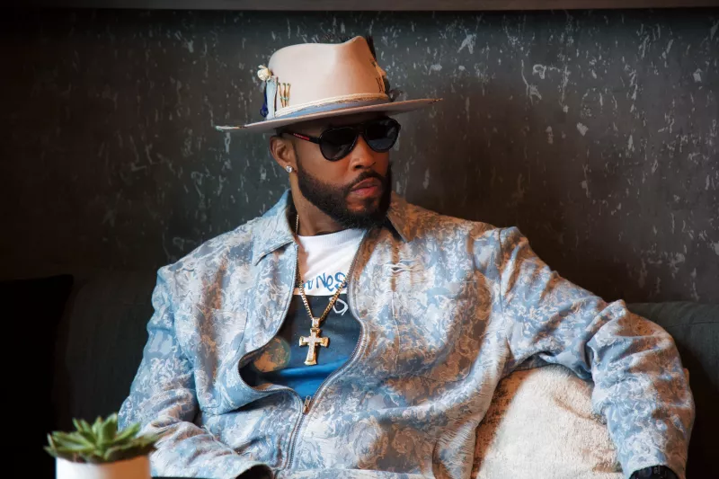 Montell Jordan in light blue jacket sitting