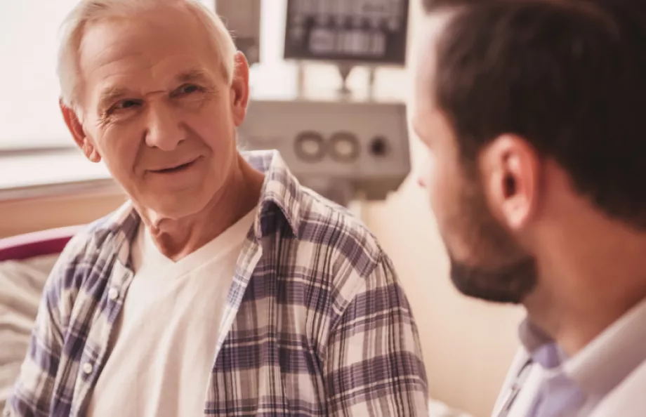 A male patient sitting on a hospital bed speaking with his doctor