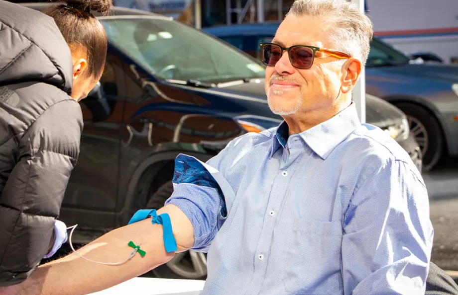 A man sitting in a chair with his arm in a tourniquet for a blood test.