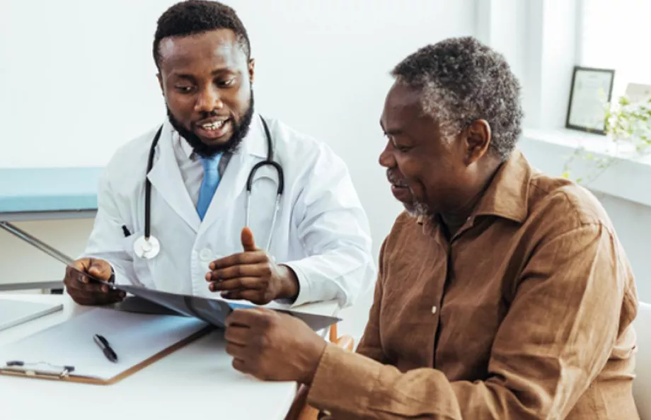 A Black man talking to his doctor at a desk