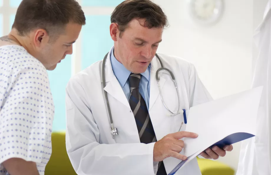 A doctor and a male patient in a gown talking