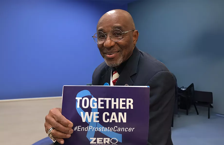 Black man holding a sign that says "Together We Can"