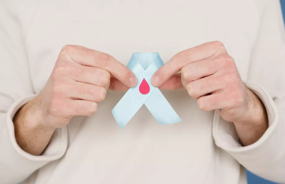 An individual in a white top holding a blue ribbon with a blood drop