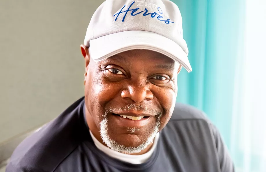 African American man wearing a white baseball hat and smiling at the camera
