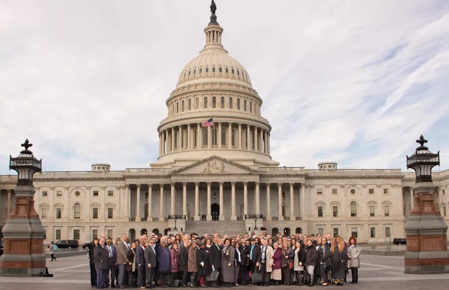 Group of people stand outside the Capitol building on a cloudy day