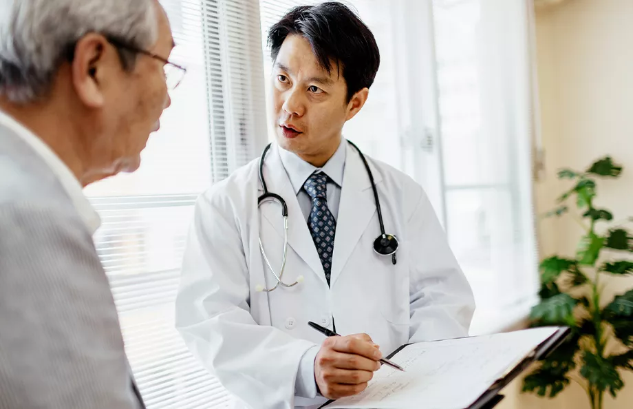 An asian doctor sitting with an older male patient