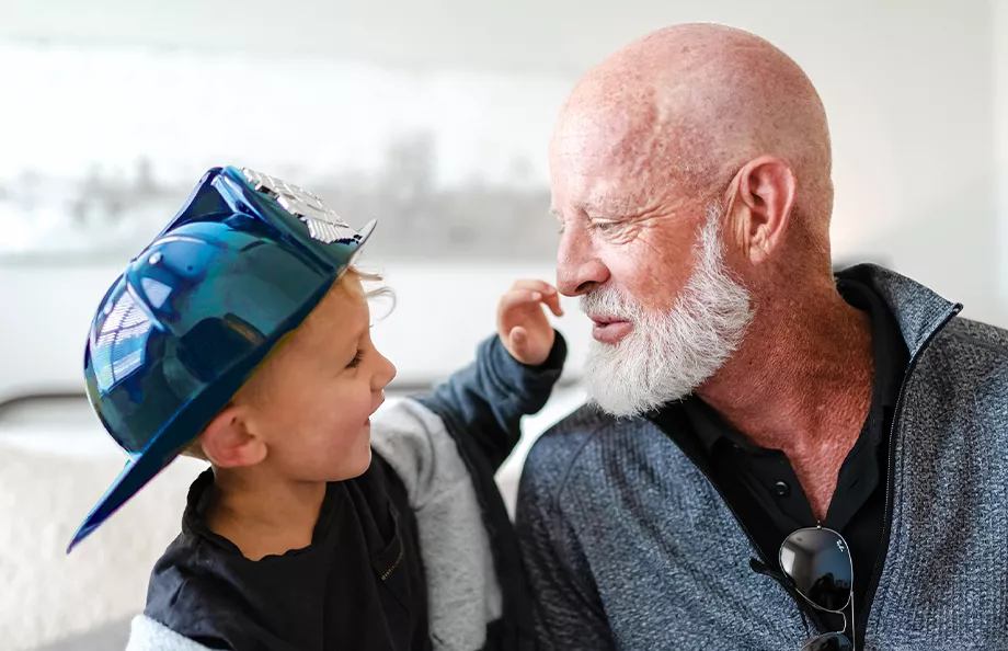 Prostate cancer survivor, Jeff, and his grandson who is wearing a blue firefighter hat