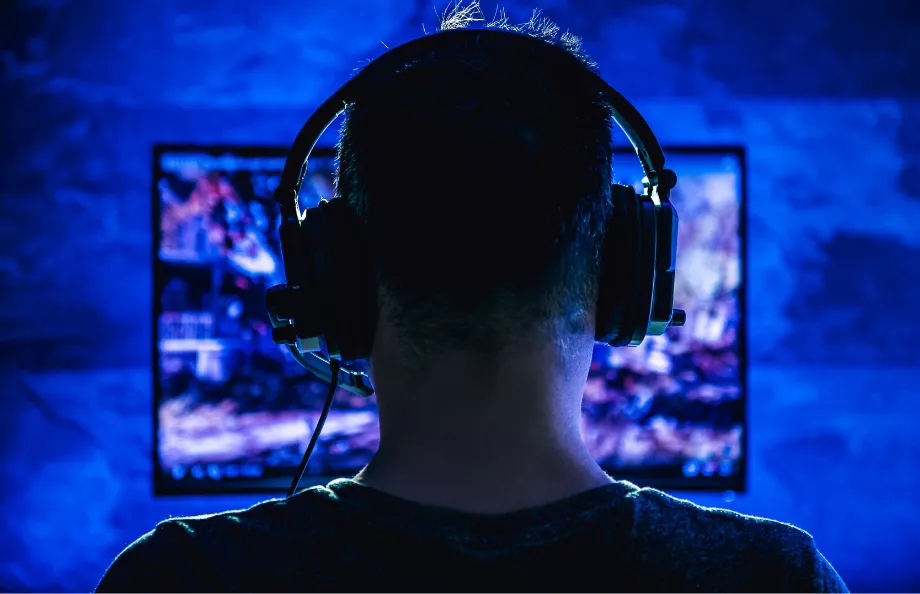 Back of man's head wearing headphones in front of a computer screen