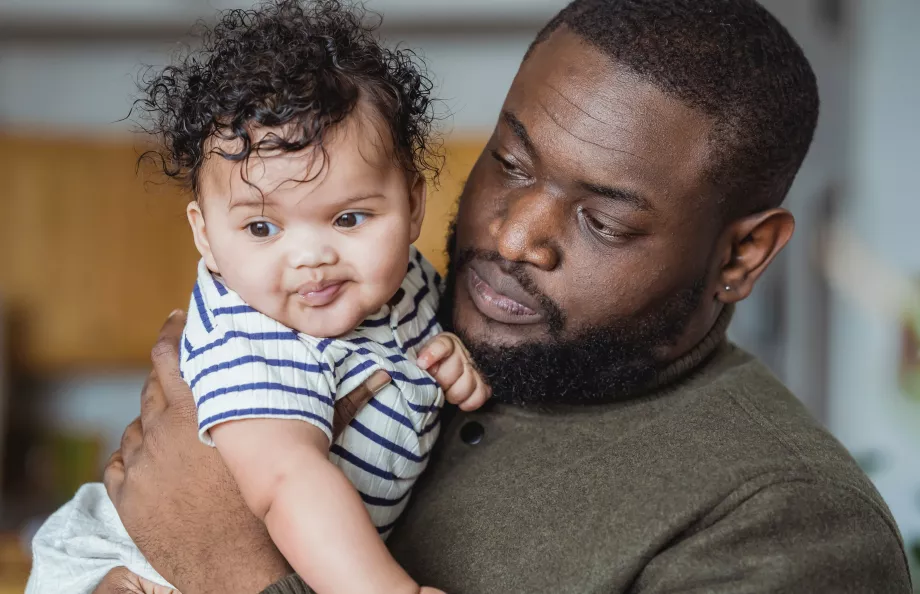 Black man holding a baby with a curly hair