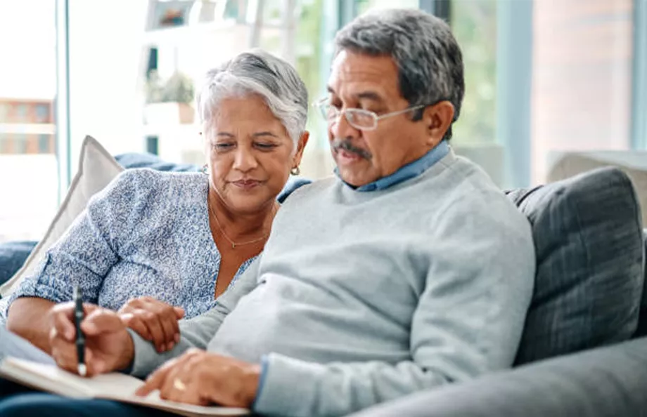 Senior hispanic couple sitting together on a couch writing