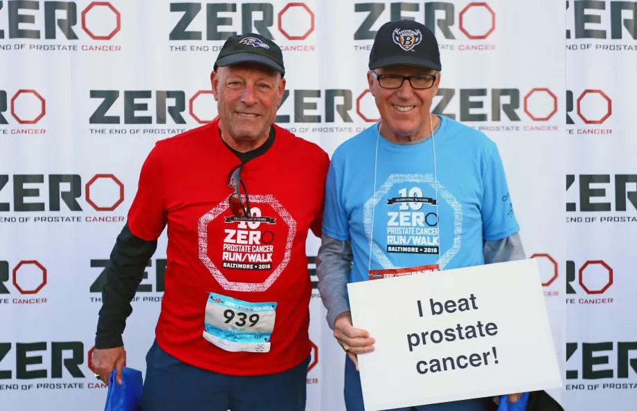 Two men in sports gear holding a "I beat cancer" sign