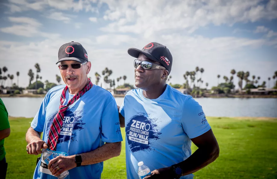 Two men in blue t-shirts and baseball hats