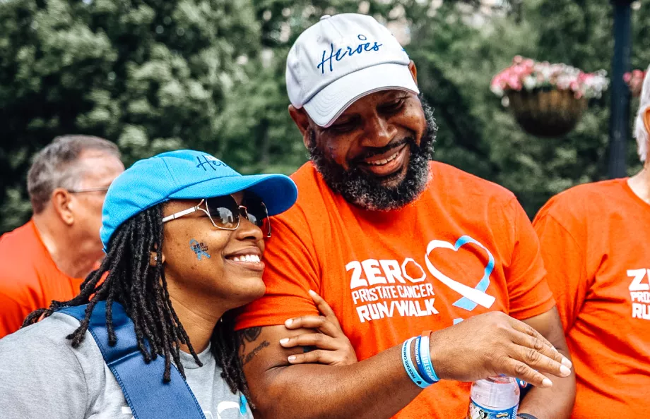 A Black couple with linked arms smiling as they walk at a Run/Walk event