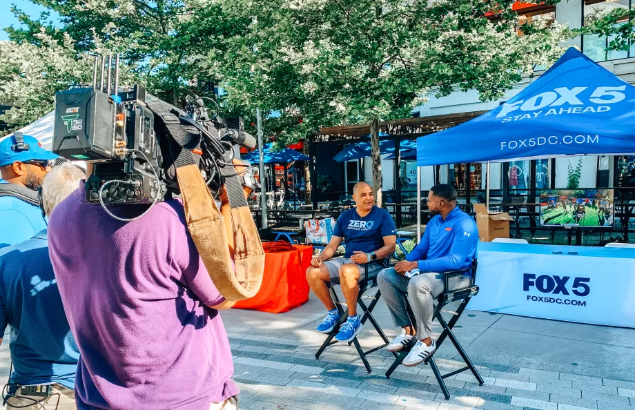 A camera person recording ZERO Champion, Eric Morrow, and a FOX 5 reporter in DC
