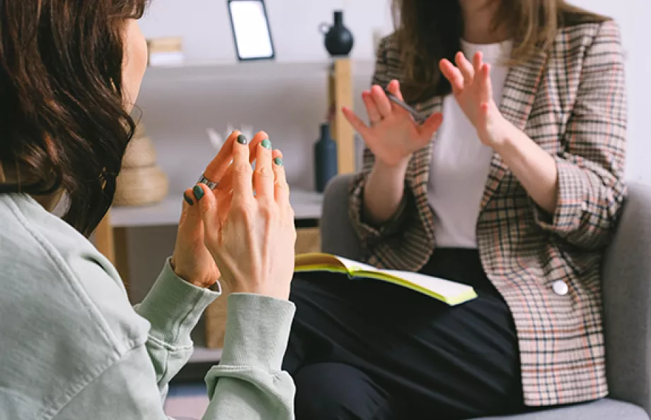two women sitting, one with a yellow notepad