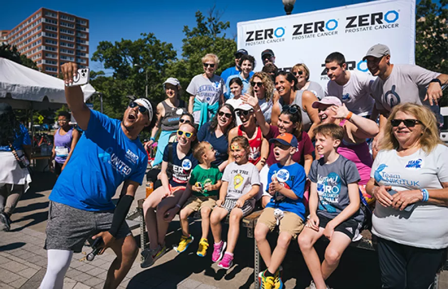 crowd taking a photo in front of banner at a run/walk