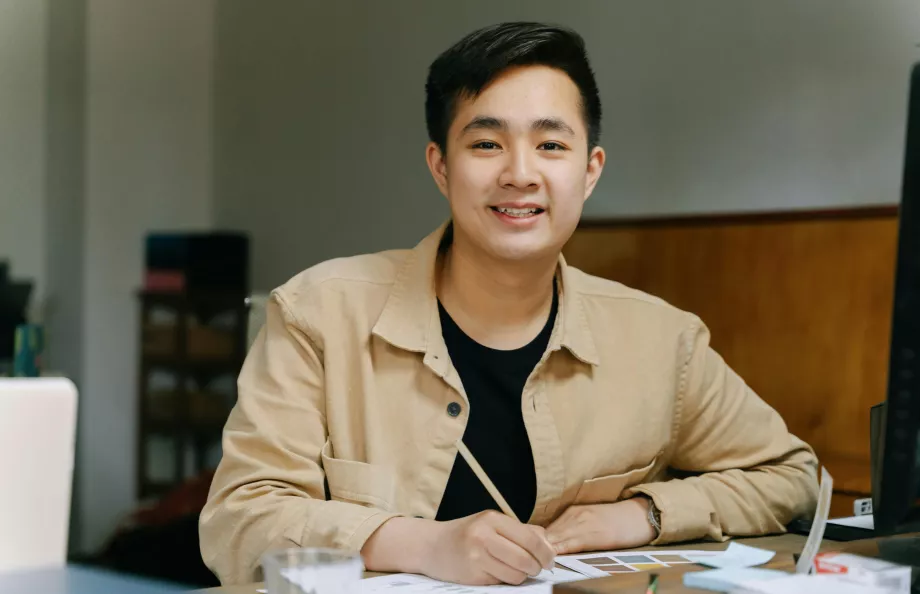 asian man smiling sitting at desk