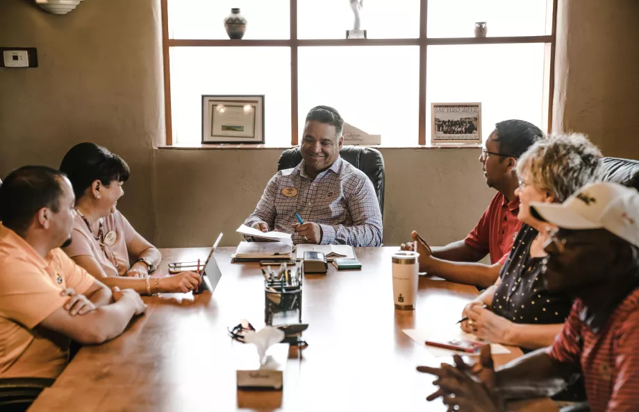 group of people sitting around a large meeting room desk