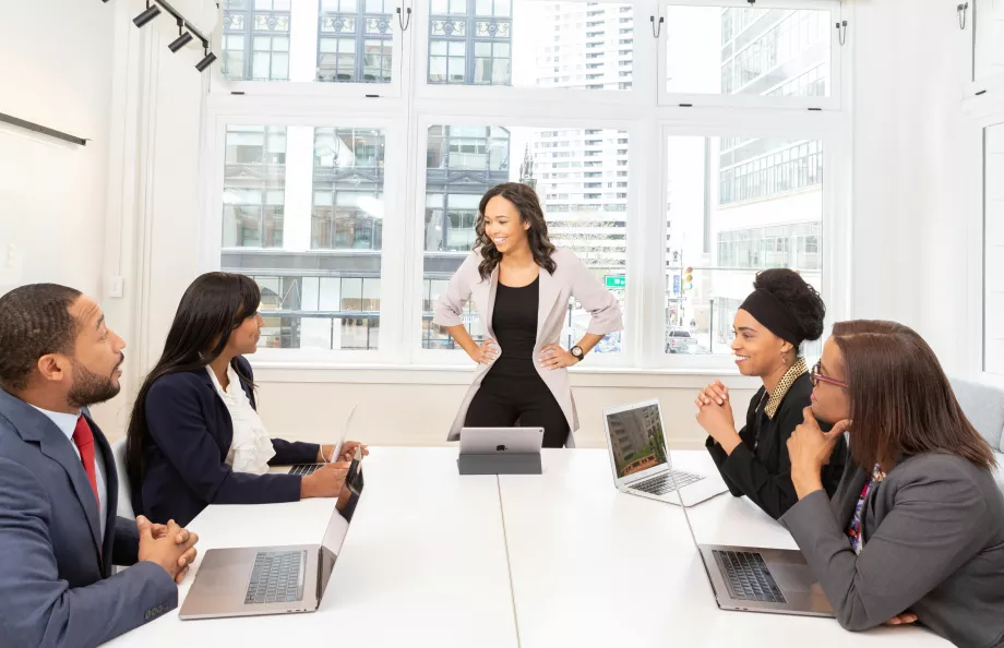 people sitting around a table in office and one woman standing up