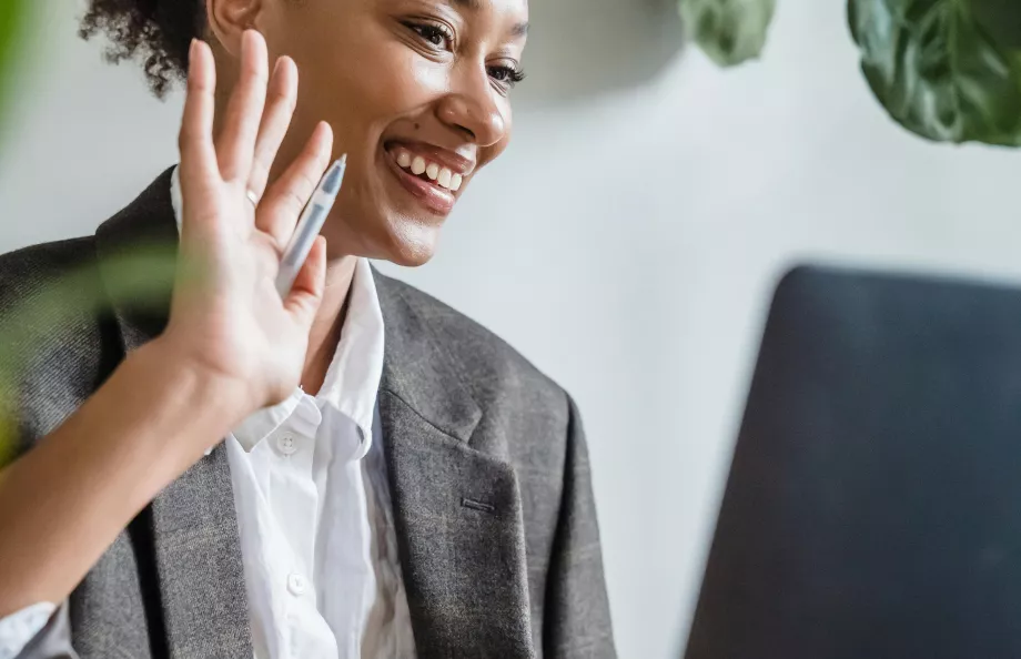 Woman waving at computer in office